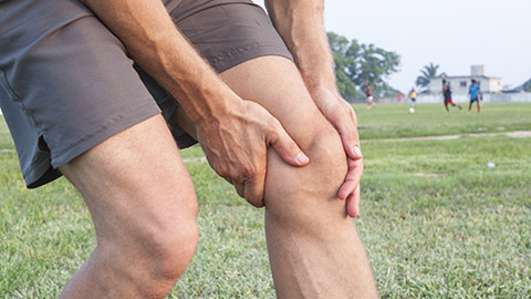 A man holding his knee in pain. 